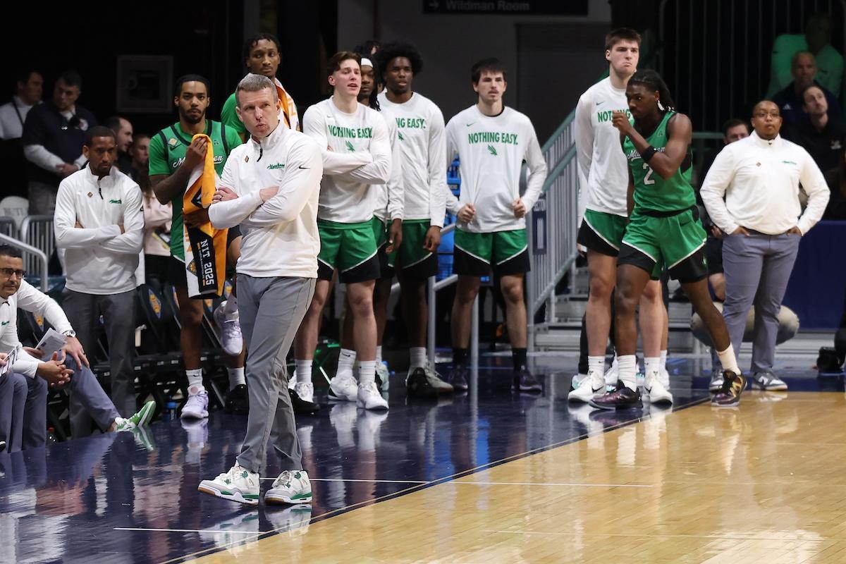 North Texas coach Ross Hodge on the sideline with players during an NIT semifinal game against UC Irvine